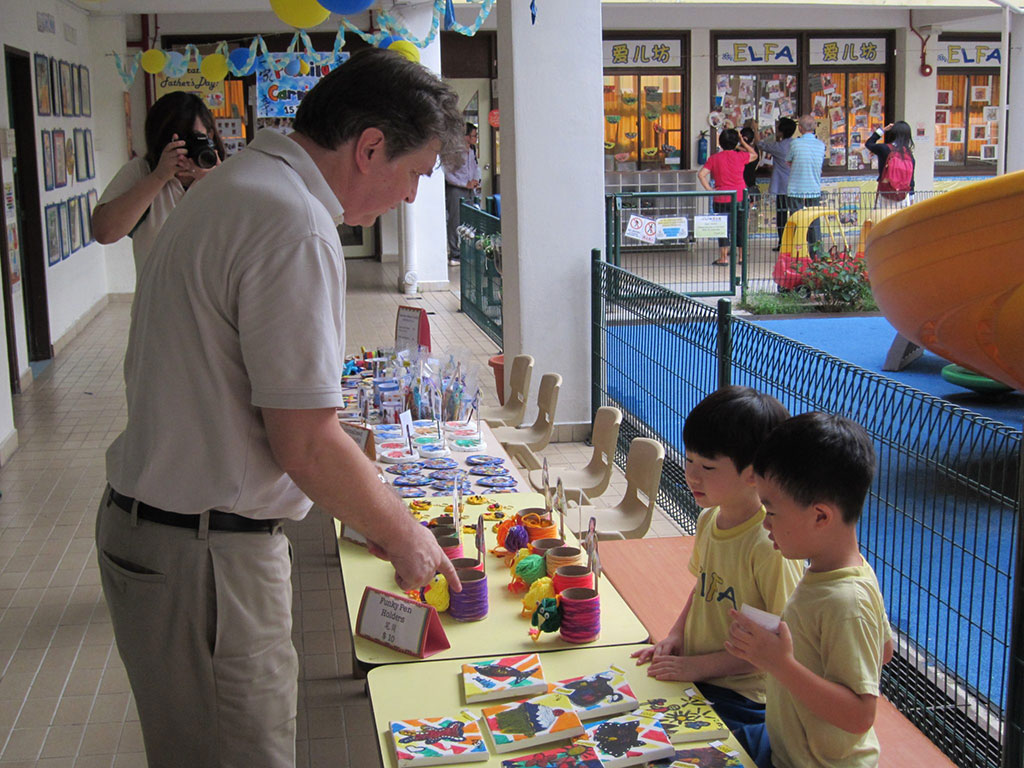 孩子们兴奋地向家长推销摊位上的手工艺品。